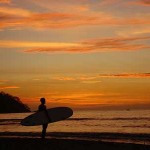 A longboard surfer watching the sunset in Guanacaste Province, in the northwest of Costa Rica.